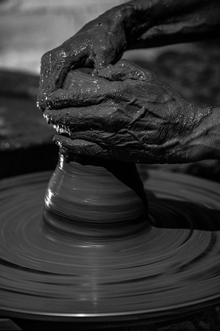 A potter's hands shaping clay on the wheel